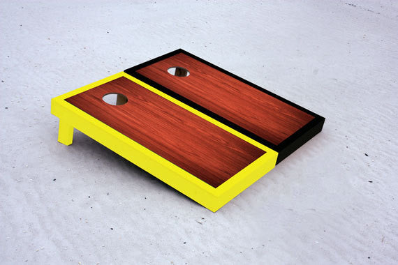Custom cornhole boards with black and yellow borders with Rosewood stained center