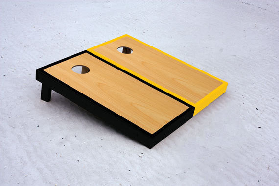 Custom cornhole boards with black and yellow borders with natural stained center